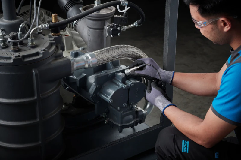 Certified technicians performing routine maintenance on a high-pressure oil-free compressor system